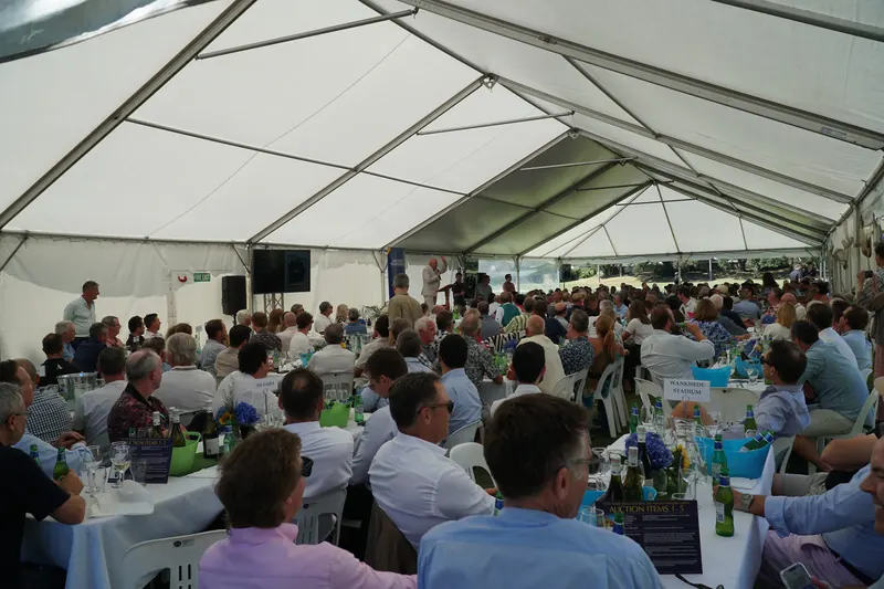 Guests seated for a corporate lunch inside a large clear-span marquee