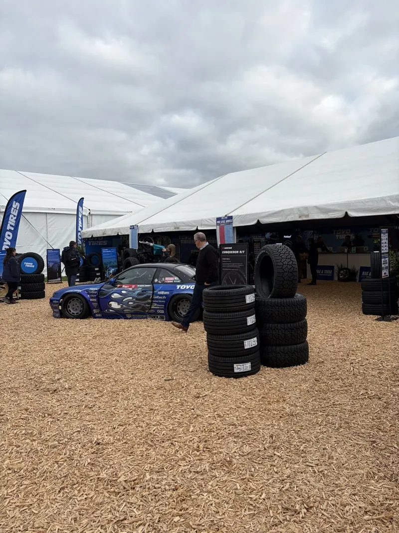 Marquees set up for a product display with a race car and stacked tyres