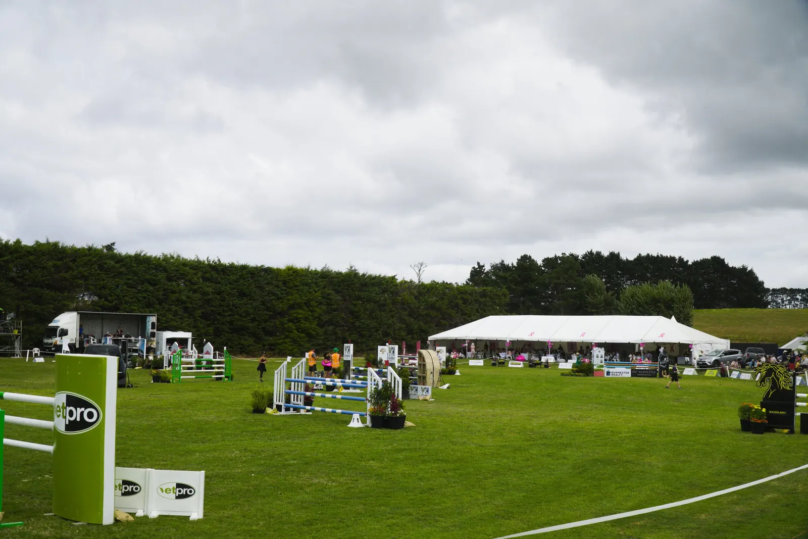 A long hospitality marquee beside a showjumping arena